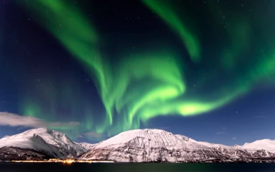 Majestuosa Aurora Boreal sobre montañas cubiertas de nieve por la noche