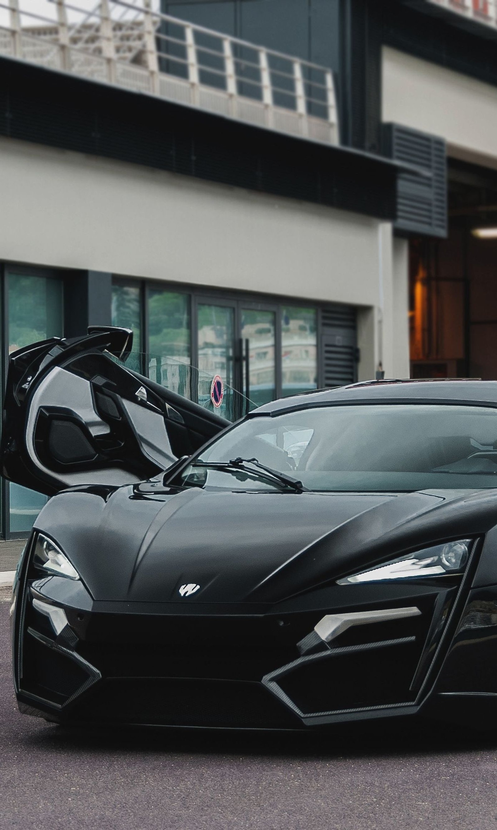 A close up of a black sports car parked in front of a building (black, cars, sports)