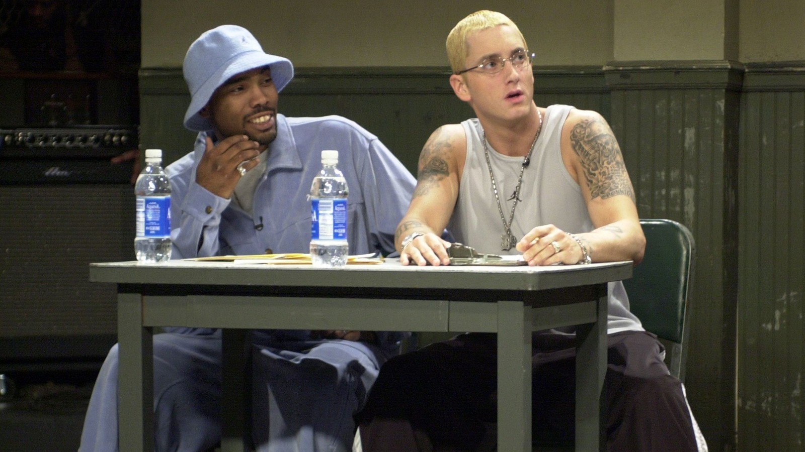 Deux hommes assis à une table avec des bouteilles d'eau (eminem, d12, rappeur, shady records)