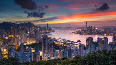 Deslumbrante horizonte do Porto de Victoria ao pôr do sol, exibindo a vibrante paisagem urbana de Hong Kong com arranha-céus imponentes e uma via navegável serena.