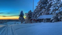 Casa de fazenda coberta de neve ao pôr do sol em uma paisagem de inverno