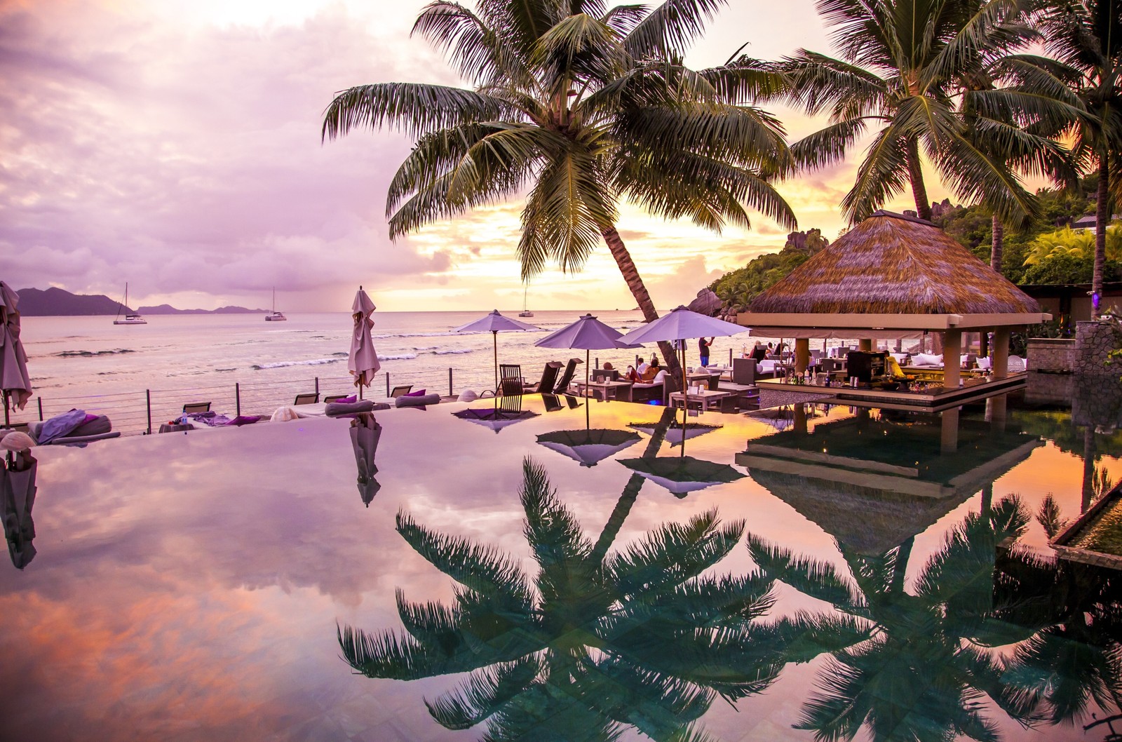 Há uma piscina com um gazebo e guarda-sóis na praia (praia, férias, estância, palmeira, trópicos)