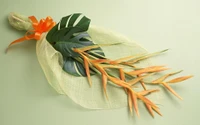 Elegant artificial flower bouquet with a vibrant orange ribbon and tropical leaves.