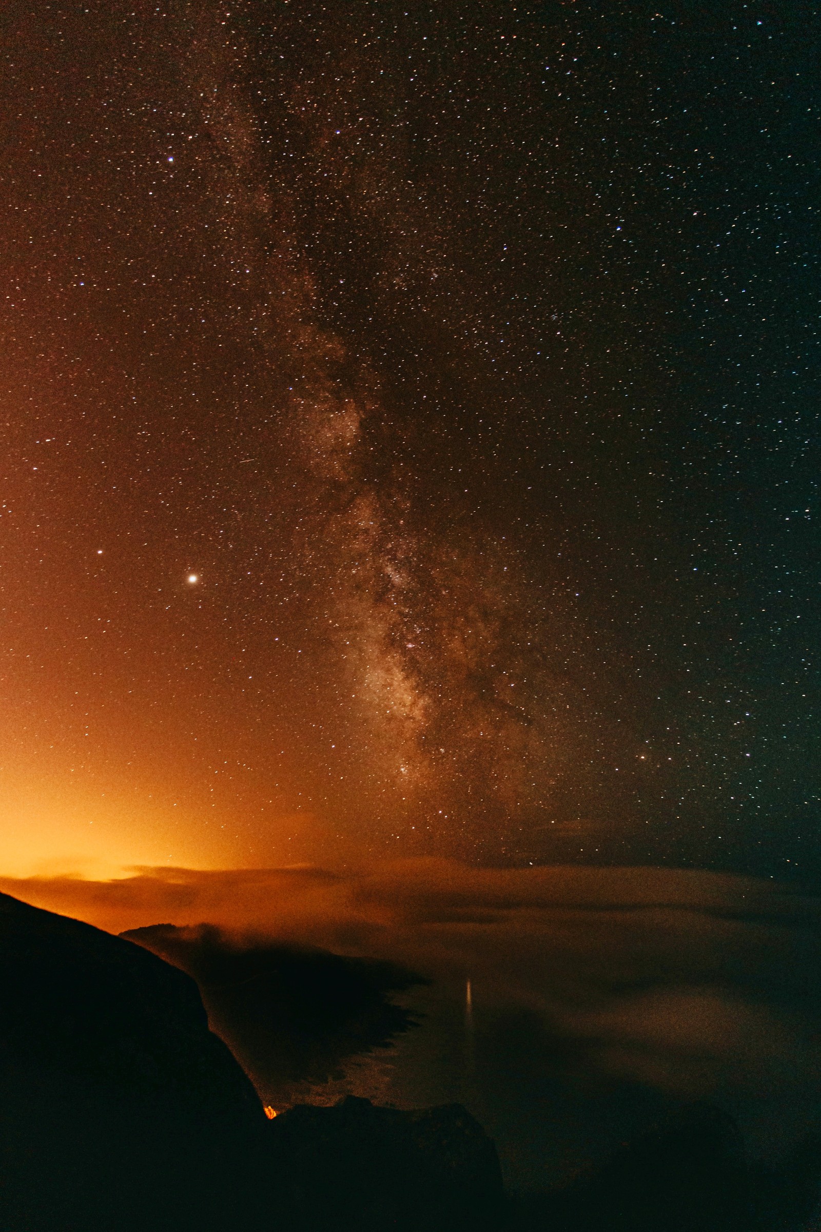 Céu estrelado com algumas estrelas sobre uma montanha e um corpo d'água (atmosfera, paisagem natural, objeto astronômico, estrela, ciência)