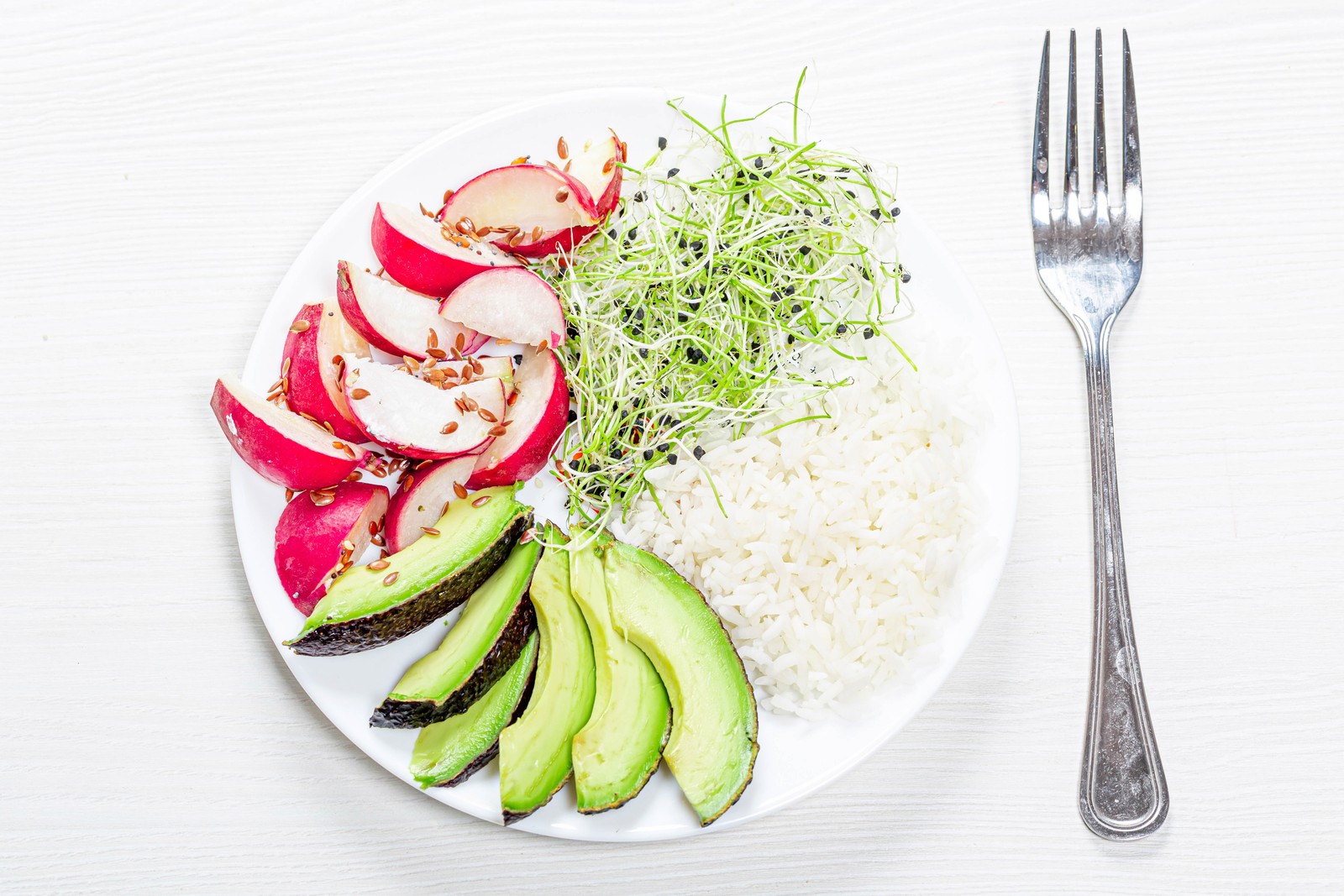 There is a plate of food with rice, avocado, and radishes (gown, vegetable, food, tableware, dishware)