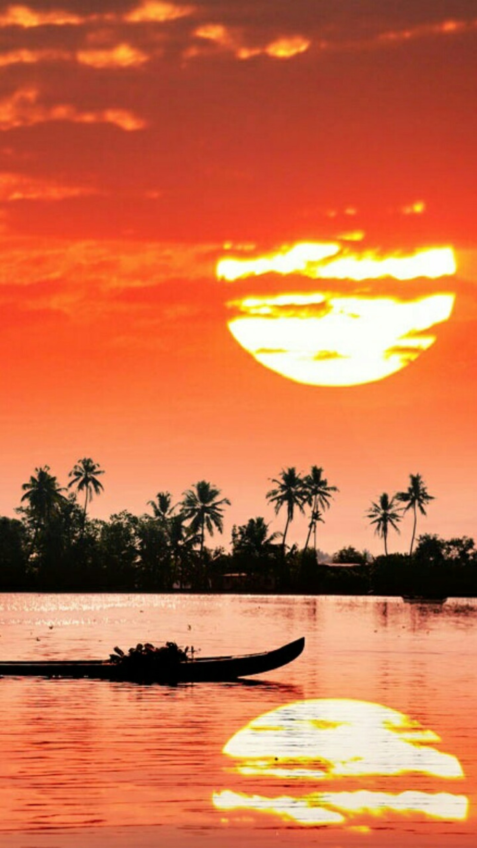 Coucher de soleil sur un plan d'eau avec un bateau au premier plan. (paysage, orange, mer, coucher de soleil)