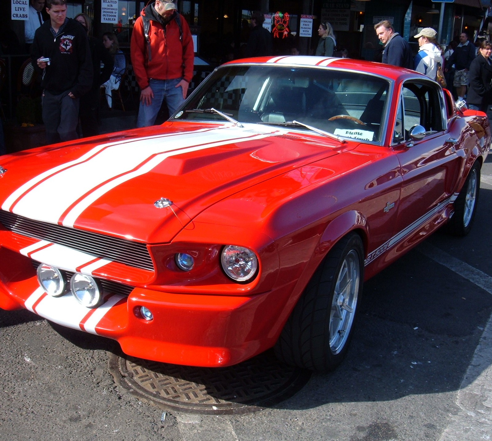 There is a red mustang car parked in a parking lot (fast too, this is cool)