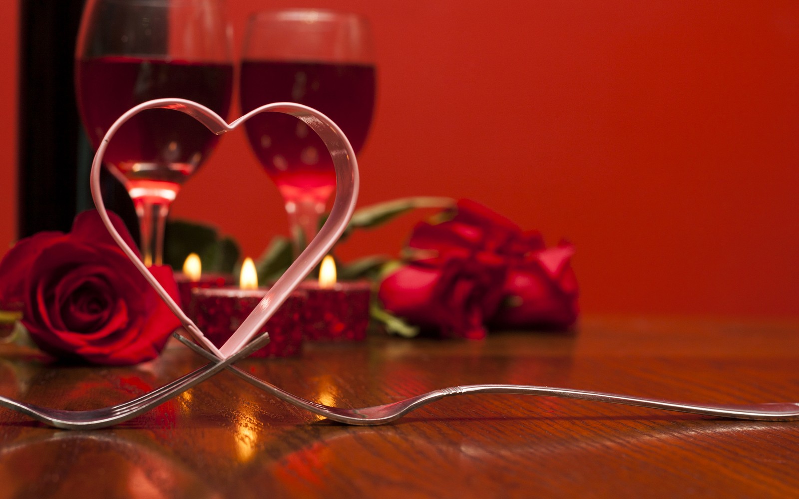 Il y a deux verres de vin et une bougie en forme de cœur sur une table (saint valentin, rouge, cœur, verrerie, amour)