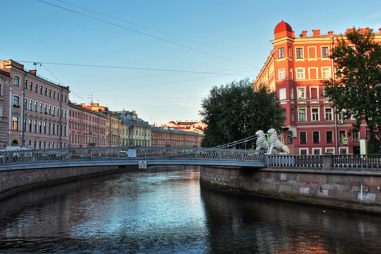 Es gibt eine brücke über einen fluss mit einem gebäude im hintergrund (reflexion, löwe, fluss, wasserstraße, kanal)