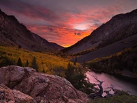 Pôr do sol vibrante sobre um sereno vale montanhoso com reflexos e cores de outono