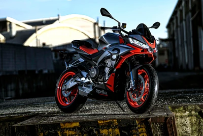 Aprilia Tuono 660 - Модель 2021 года в ярком красном и серебристом цветах на фоне промышленного пейзажа