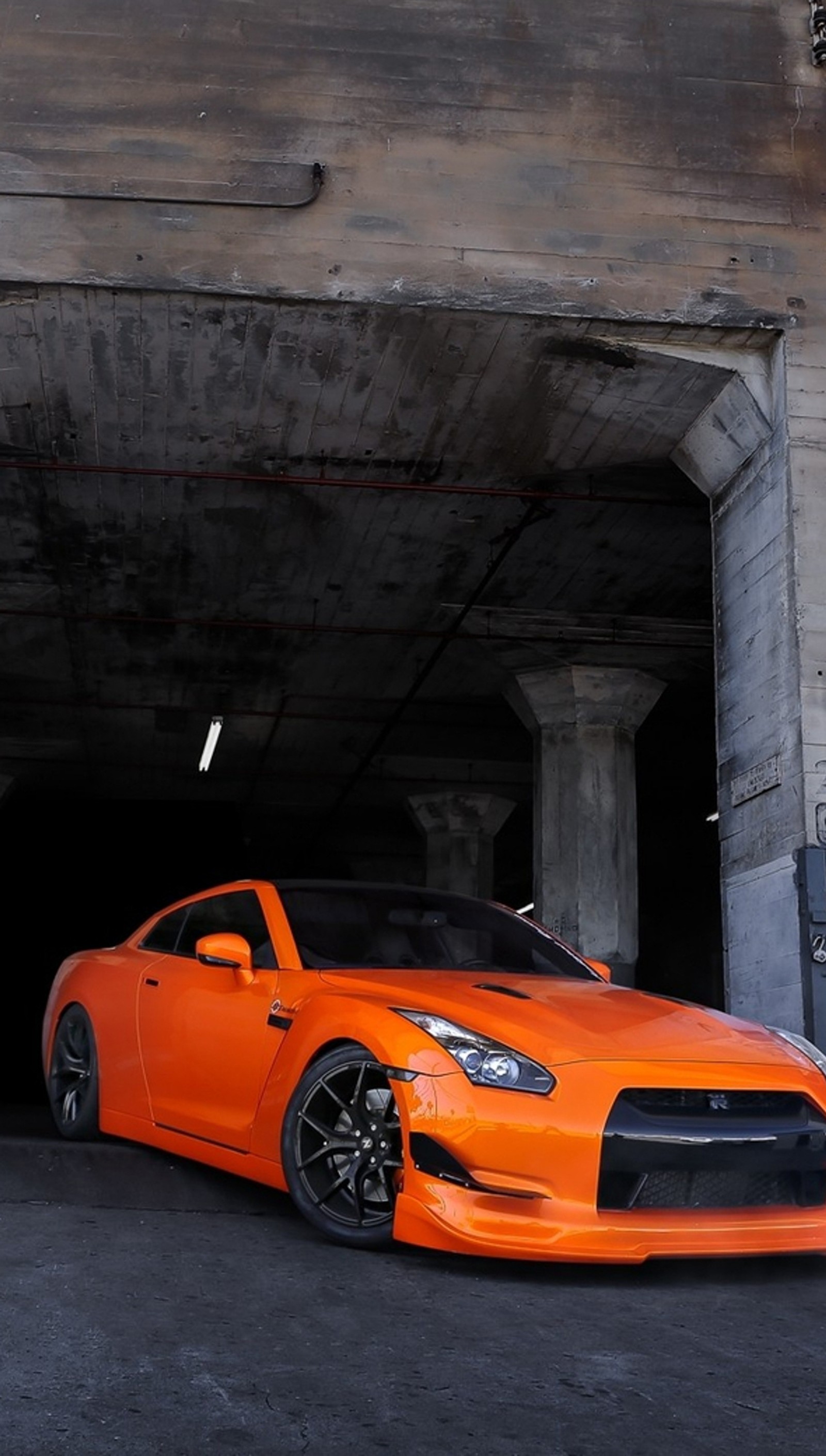 Arafed orange sports car parked in a garage with a concrete wall (car, gt r, nissan, orange)