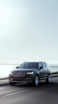 Volvo XC90 внедорожник в движении на фоне спокойного пейзажа