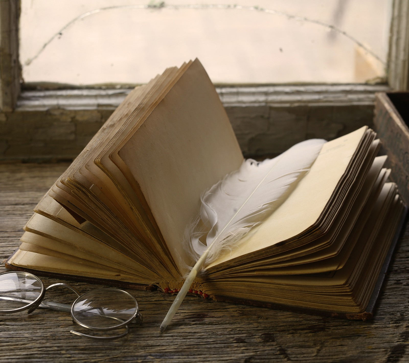 Il y a un livre avec une plume et des lunettes sur une table (livre, plume, lire)