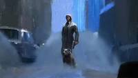 A lone figure in a suit stands in a rain-soaked urban landscape, accompanied by a dog, exuding a sense of determination amidst the chaos.