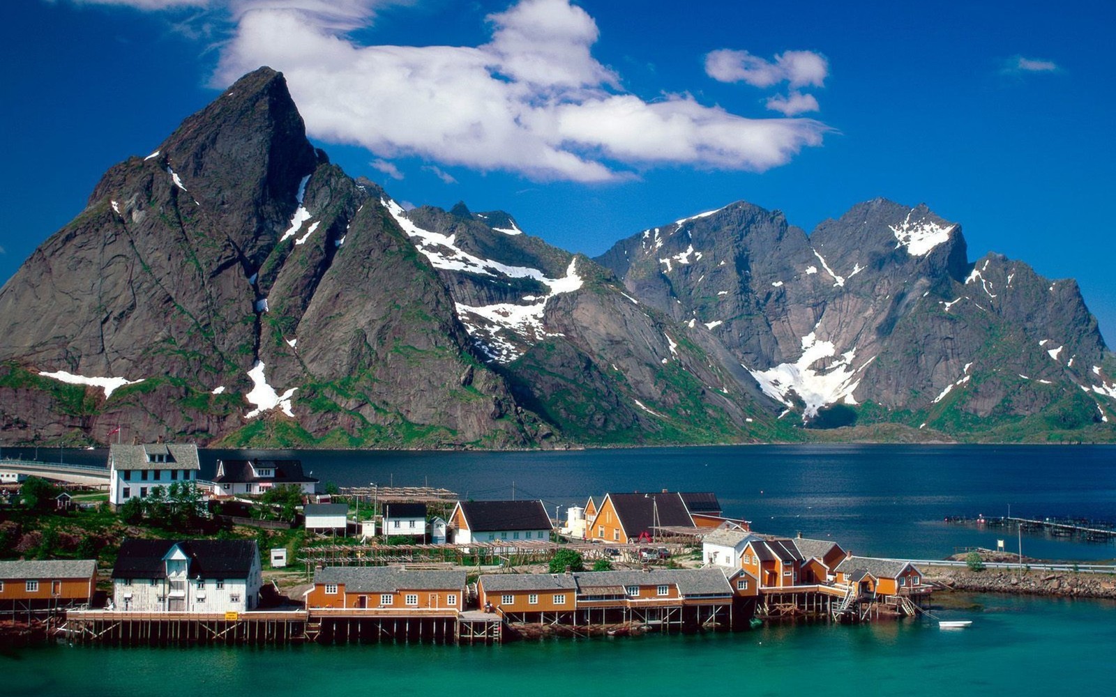 Vista de un pequeño pueblo con montañas de fondo (lofoten, montaña, naturaleza, cordillera, escenario montañoso)