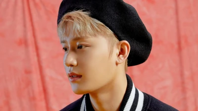 Moon Taeil de NCT 127 con una boina elegante, capturado contra un vibrante fondo rosa.