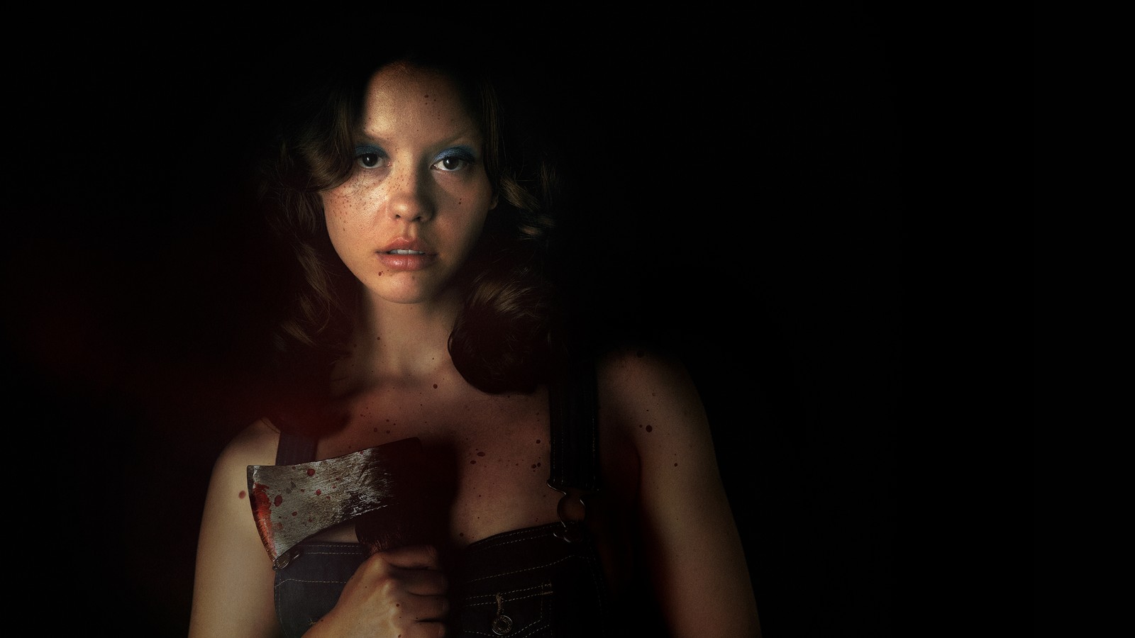 Há uma mulher segurando uma faca no escuro (x, mia goth, filmes 2022, filmes de terror, fundo escuro)