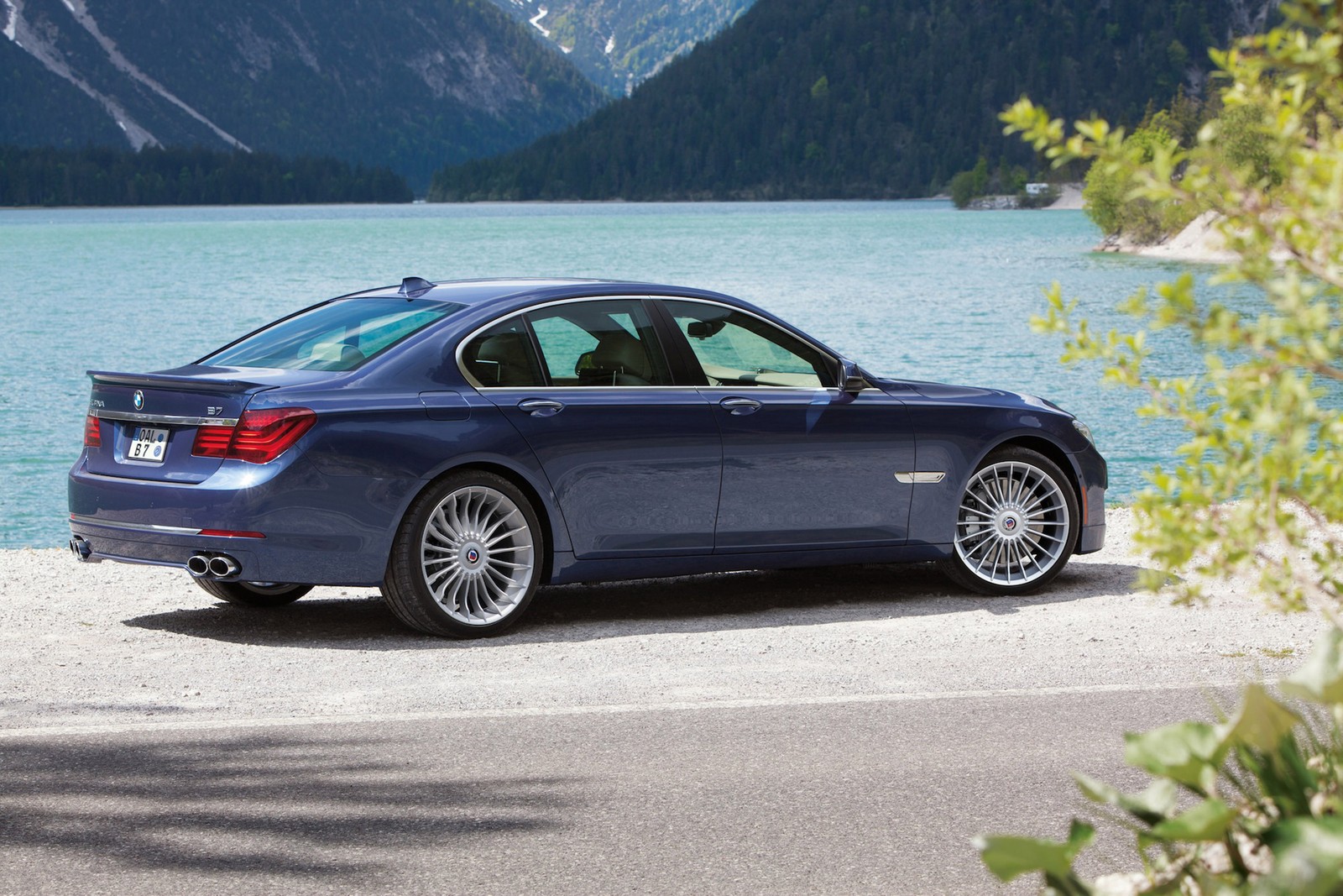 Un primer plano de un coche bmw azul estacionado cerca de un lago (coche, bmw, coche ejecutivo, llanta, coche de lujo)