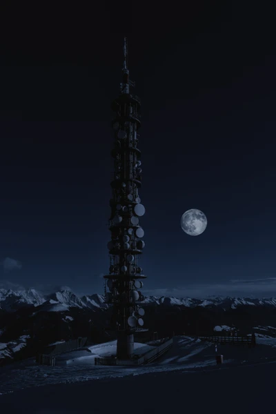 Torre iluminada bajo una luna llena en un cielo estrellado