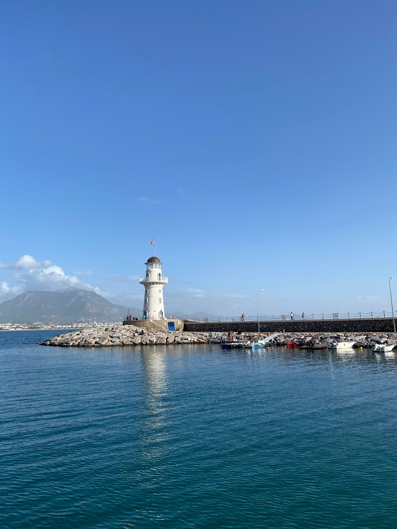 На берегу гавани с лодками стоит маяк (море, вода, облако, маяк, водные ресурсы)