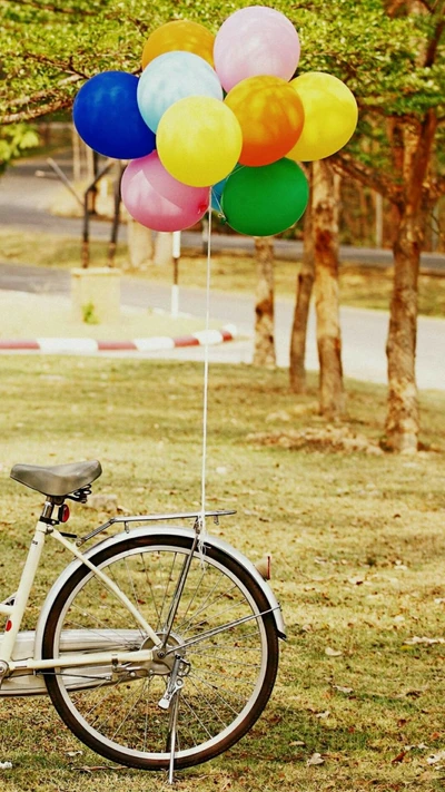 Balões coloridos amarrados a uma bicicleta vintage em um parque verdejante