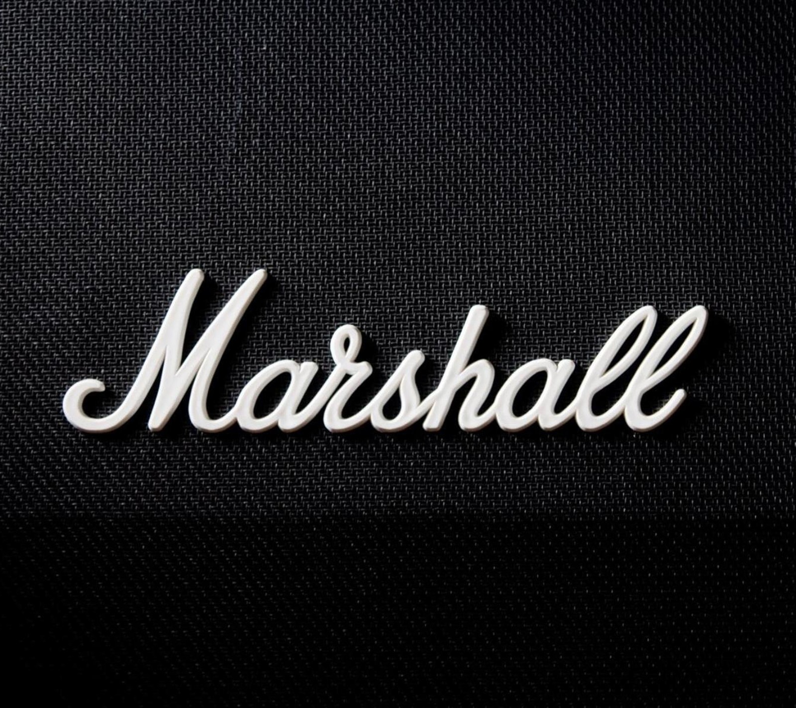 Un primer plano del logo marshall en una tela negra (amp, amplificador, negro, marca, logotipo)