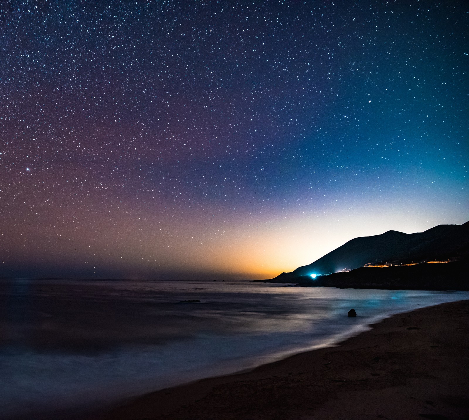 Céu noturno sobre o oceano com uma praia e uma montanha ao fundo (costa, noite, céu noturno, mar, horizonte)