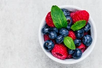 Frische Blaubeeren und Himbeeren mit Minze in einer Schüssel