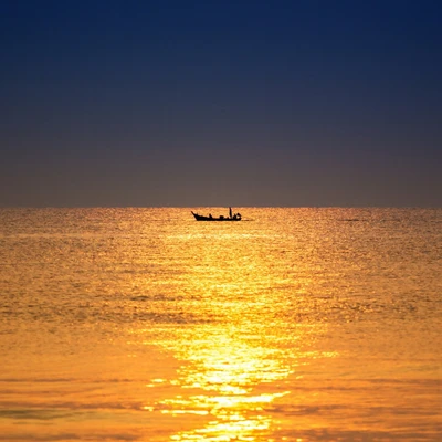 Glowing Dusk: A Boat Glides Across an Amber Ocean Surface