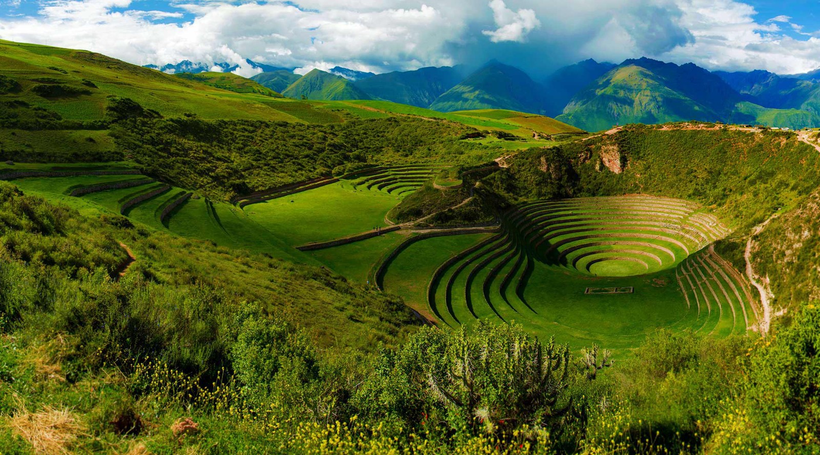 Um grande campo verde com uma grande estrutura circular no meio (machu picchu, império inca, terras altas, vegetação, paisagem)