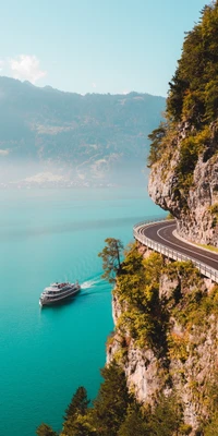 Estrada cênica à beira do lago com um barco navegando em águas azuis em meio aos Alpes suíços.