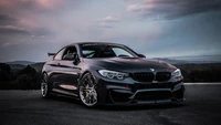 Sleek BMW M4 sports car showcased against a dramatic twilight backdrop, highlighting its aerodynamic design and custom rims.