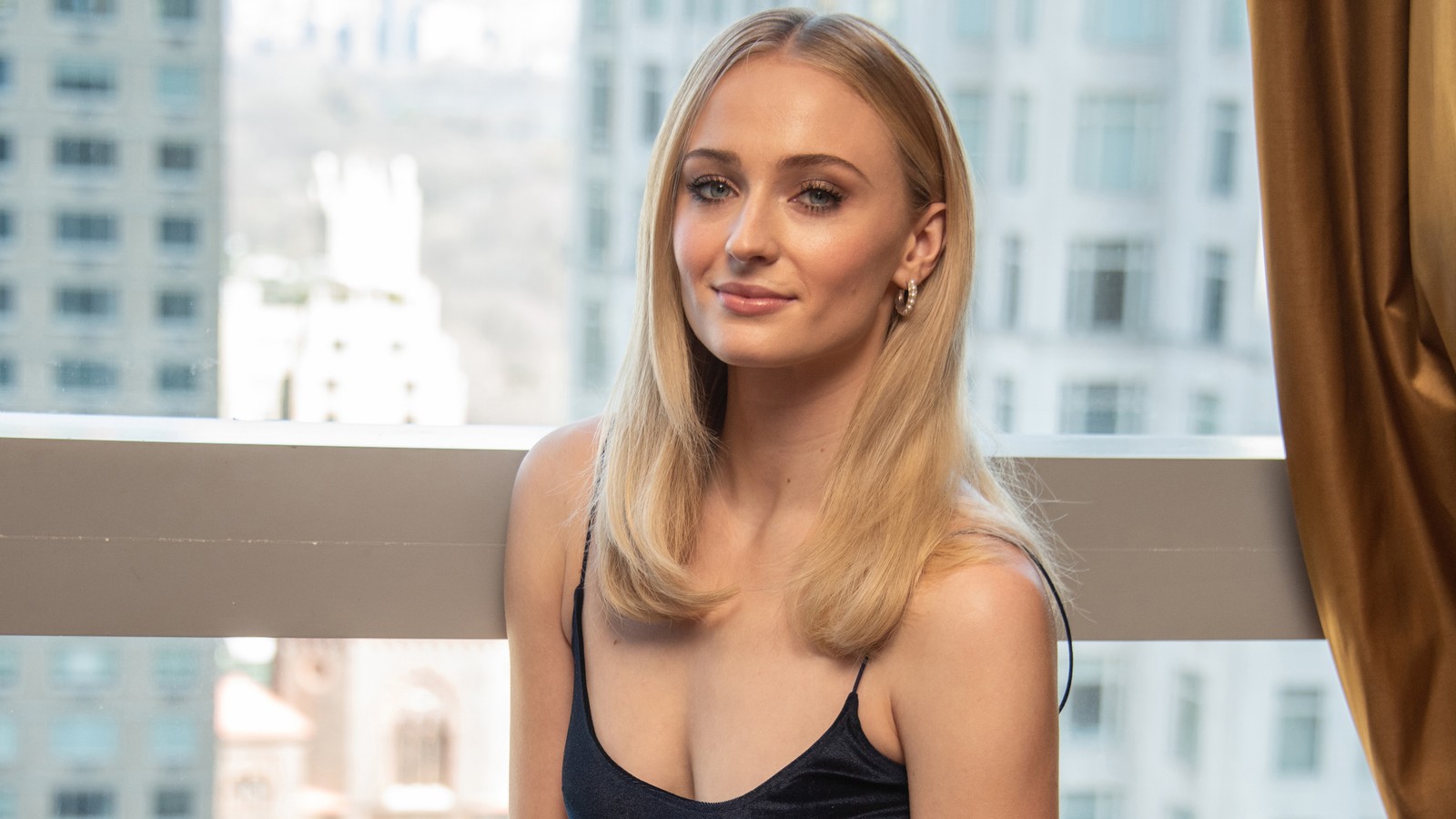 Femme arabe en robe noire assise devant une fenêtre (sophie turner, blonde, actrice, célébrité, femmes)