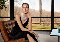 Dama elegante en un vestido negro adornado con un collar de perlas llamativo y un broche de piedras preciosas, mostrando belleza y moda atemporales.