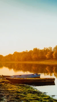 Reflexão serena à beira do lago com barcos ao anoitecer