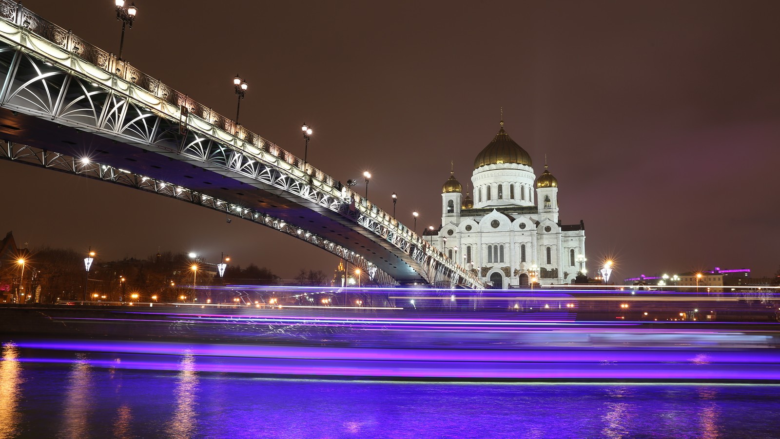 Una vista arafada de un puente con un bote pasando por debajo (noche, hito, puente, reflexión, ciudad)