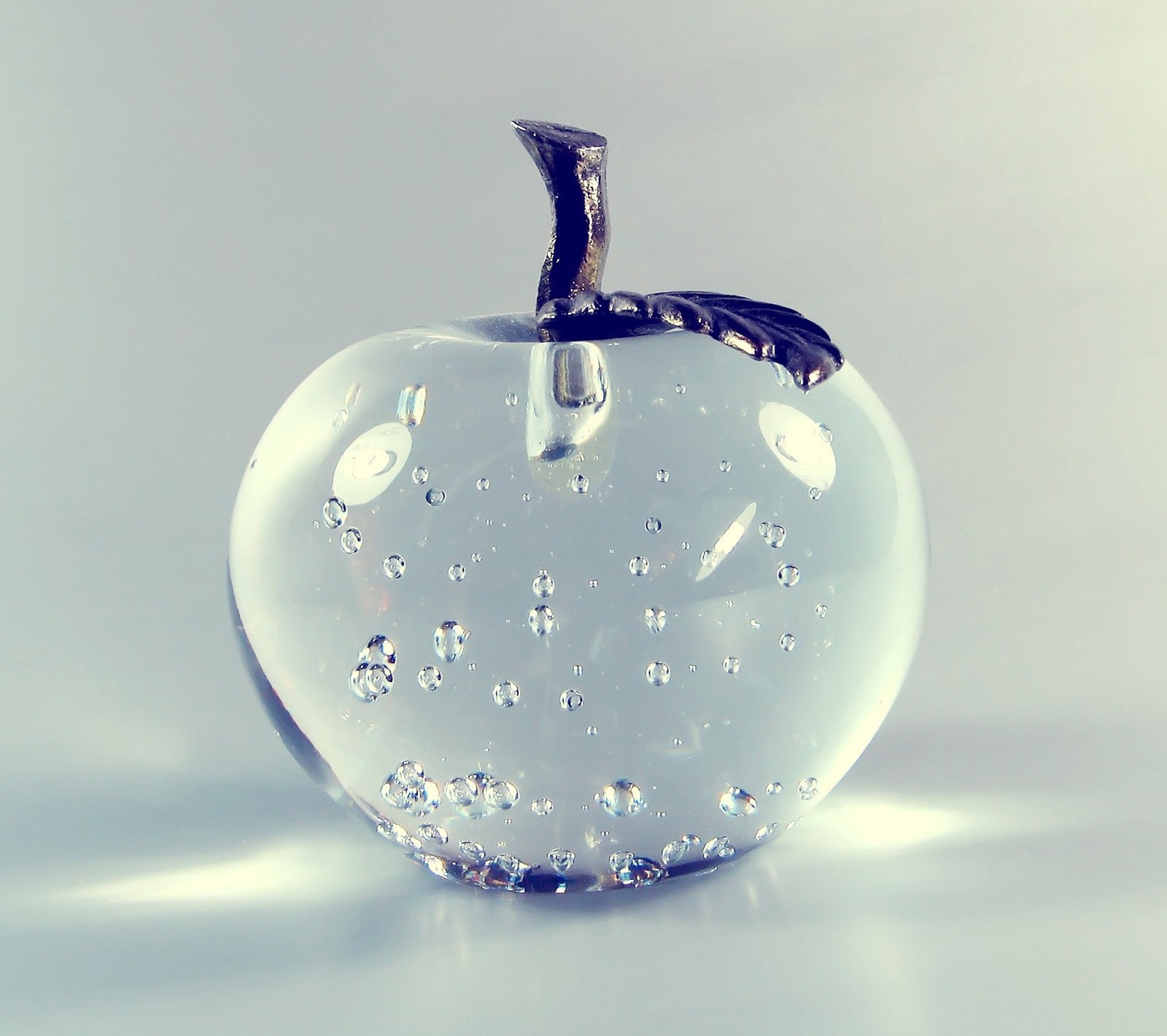 There is a glass apple with a leaf on it (apple, white)