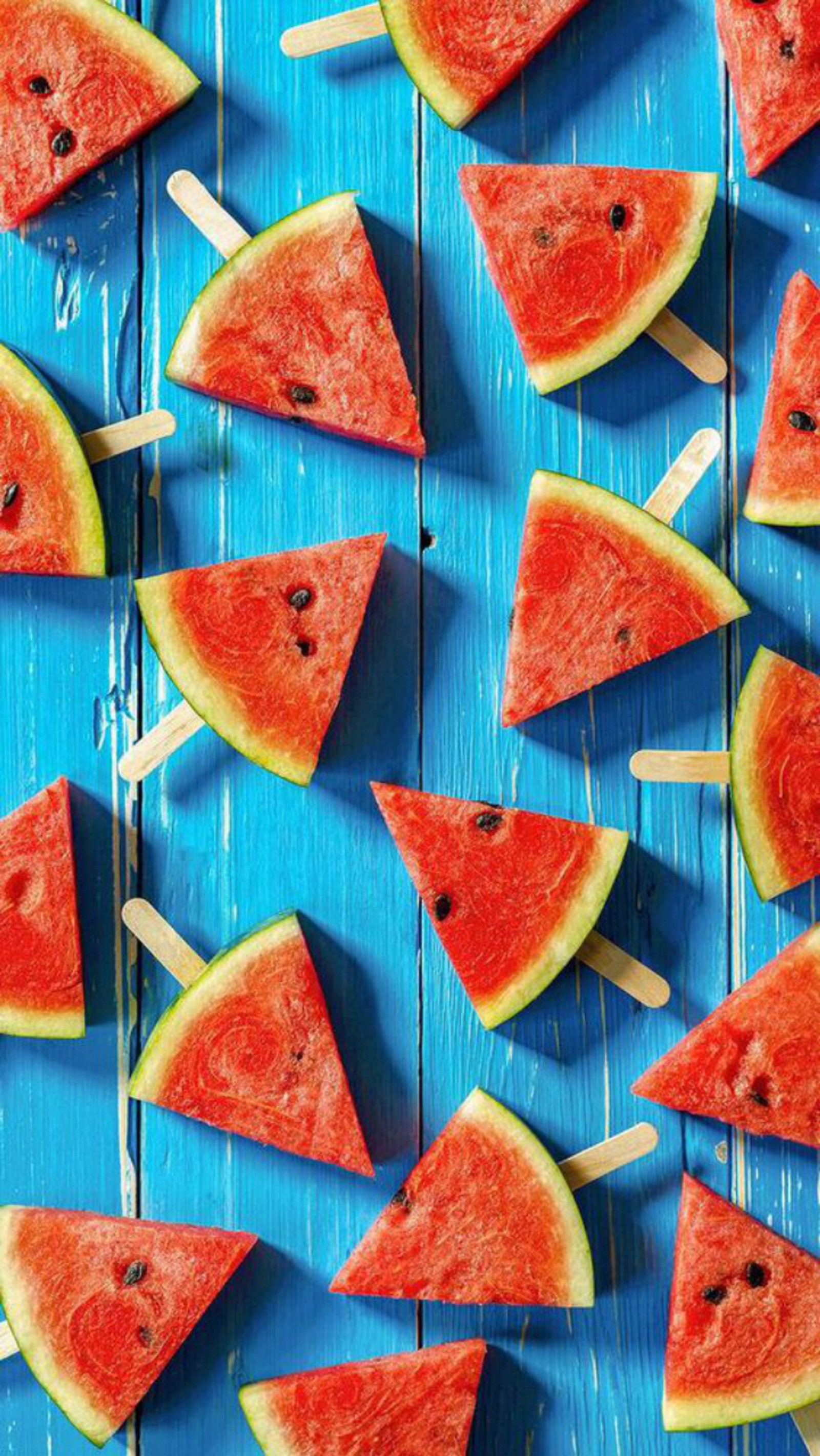 Slices of watermelon on a stick on a blue wooden table (fruits, watermelons)