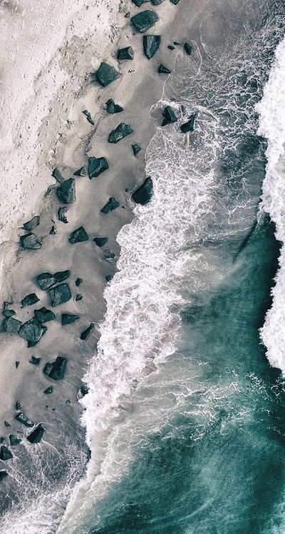 Vista aérea de una playa serena con suaves olas que golpean la costa rocosa.