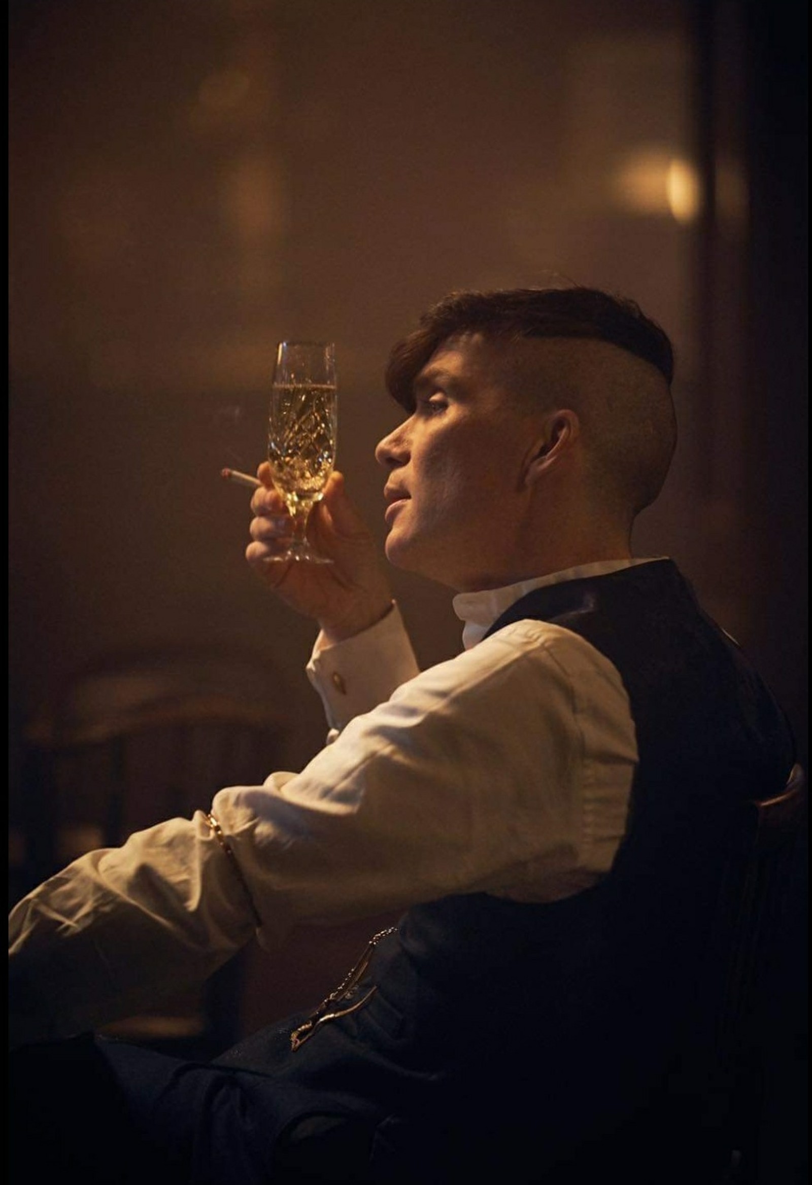 Há um homem sentado bebendo um copo de vinho (peaky blinders, thomas shelby)