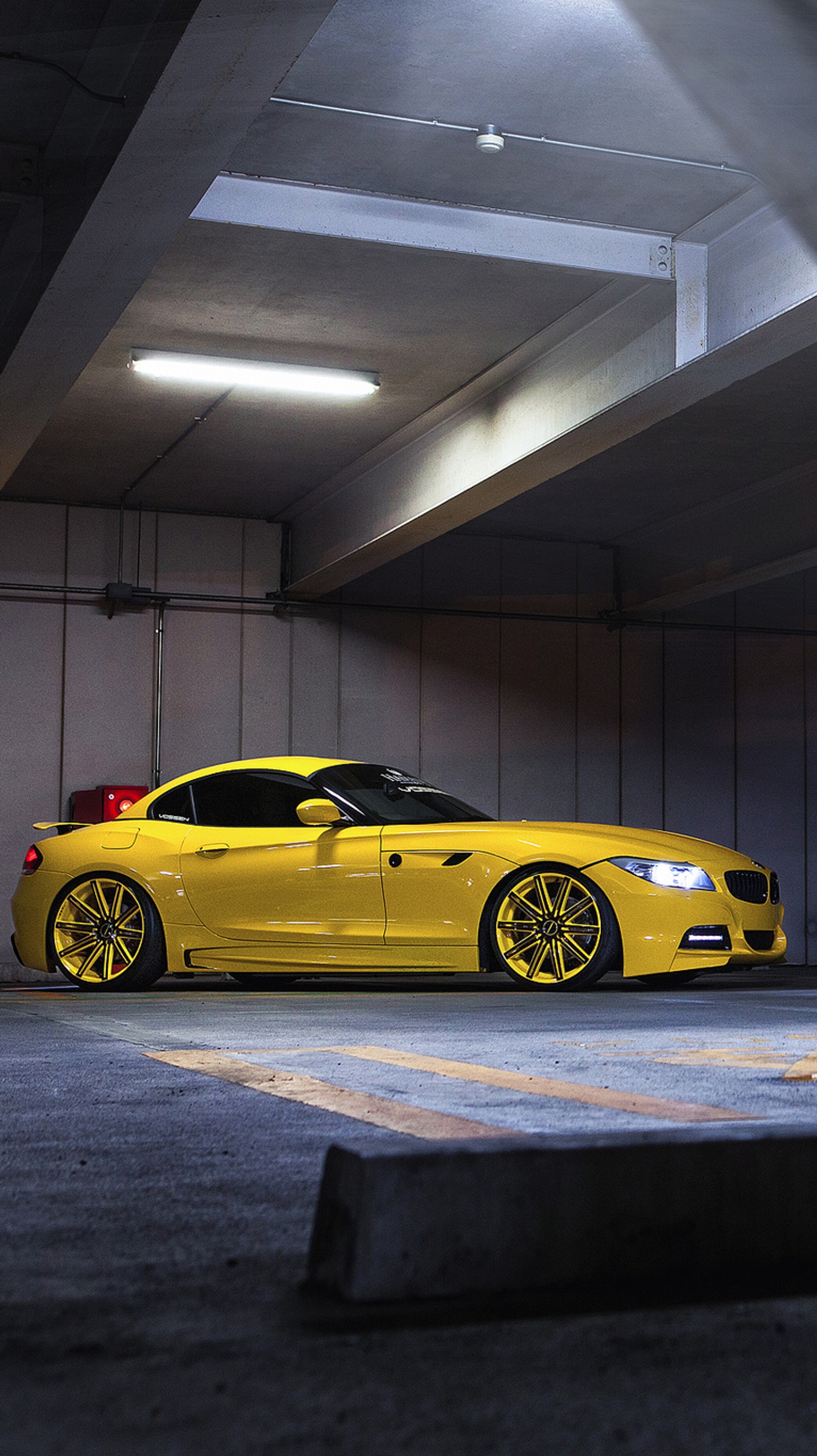 Um carro bmw amarelo estacionado em uma garagem com luz vermelha (bmw, carro, esporte, amarelo)