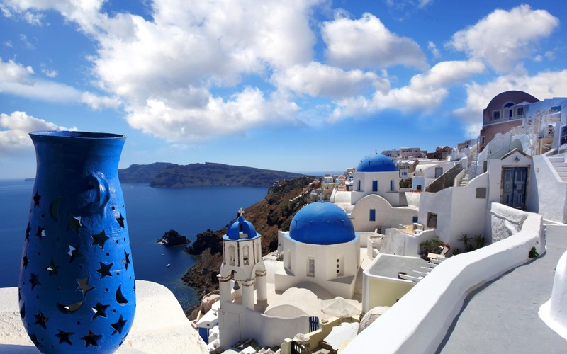 Vista arafed de um vaso azul em uma parede branca com vista para uma cúpula azul (santorini, férias, nuvem, dia, água)