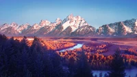 Majestätische Grand-Teton-Berge spiegeln sich in einem ruhigen Fluss zwischen lebhaften Herbstwäldern