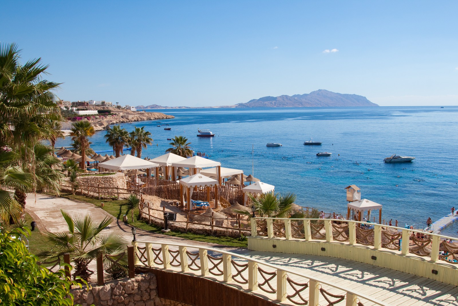 Vista de uma praia com uma ponte e palmeiras (hurghada, turismo, mar, costa, férias)