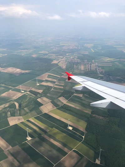 Vue aérienne de champs en patchwork et d'éoliennes depuis la fenêtre d'un avion