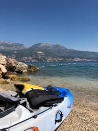 Línea de costa tranquila con kayak de mar y vista de montaña