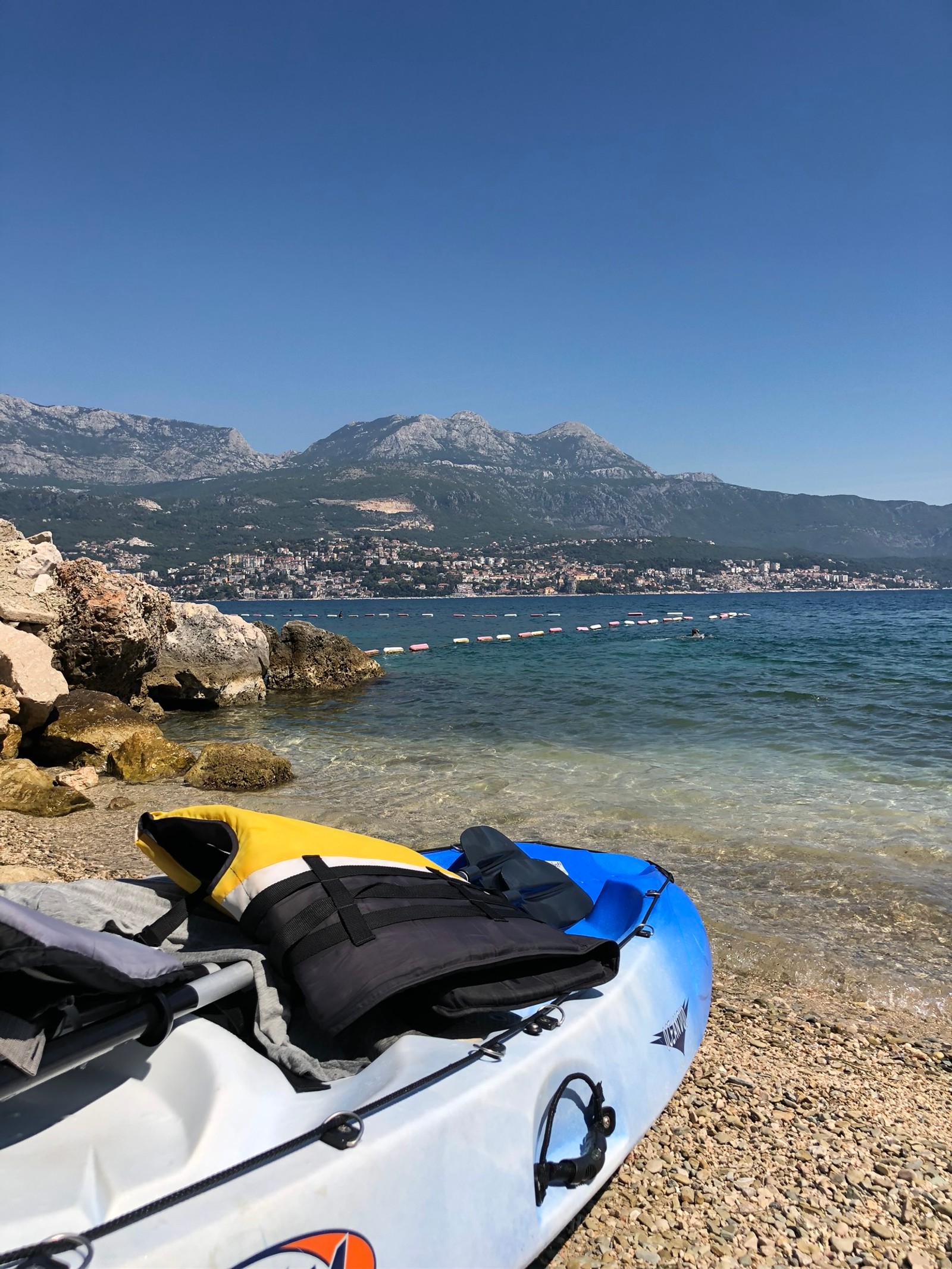 Há um caiaque na praia com uma montanha ao fundo (carros, barco, água, caiaque, turismo)