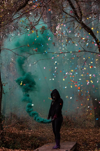 Silhouette in einer Gasmaske zwischen buntem Rauch und Wald