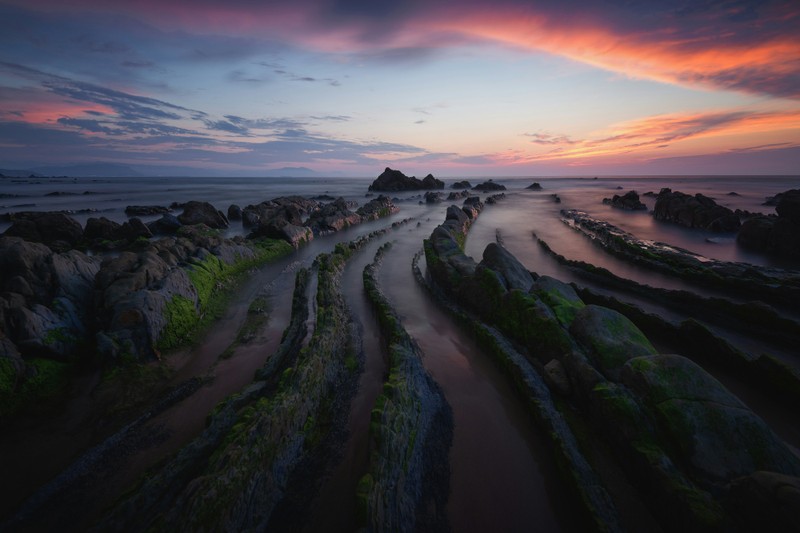 Вид на пляж с камнями и водой на закате (barrika beach, закат, испания, скалистый пляж, природа)